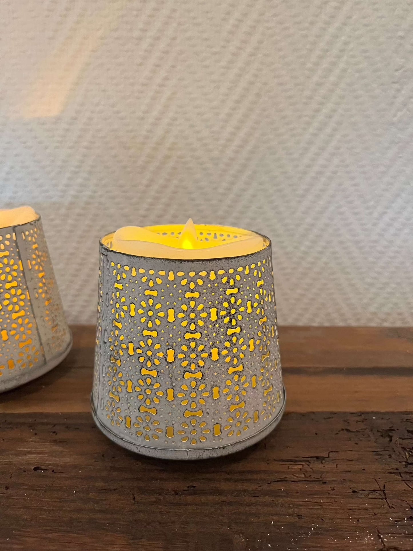 White metal windlicht with floral cutouts creating cozy ambiance.