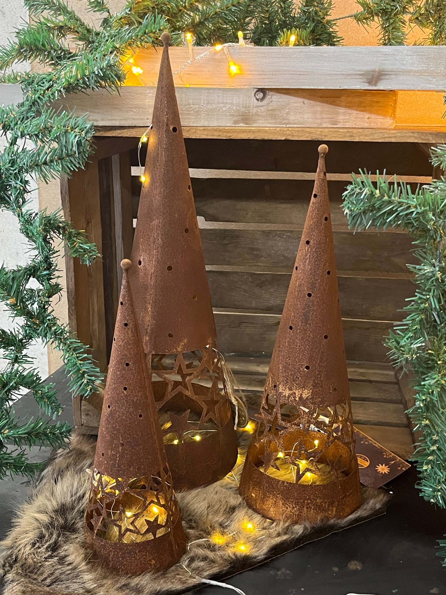 Dekoaufsteller Pyramide aus Rostmetall mit Sternausschnitt in drei Größen und weihnachtlicher Beleuchtung.